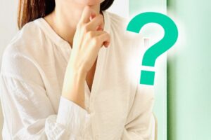 顎に手を添えて悩み、考え込む女性の様子と、その横に大きく描かれた疑問符（クエスチョンマーク）。夫婦関係において「なぜ会話が噛み合わないのか」という悩みを抱え、解決の糸口が見つからず、心の距離や本音が言えない現状に戸惑う40代女性の心情を表現した画像。