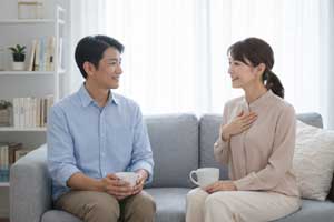 リビングで向き合い対話する夫婦。表面的な会話の悩みを超えて、お互いの本音を探り、心のつながりを取り戻そうとする40代女性の切実な願いと、関係修復に向けた真摯なコミュニケーションの重要性を伝える一場面。